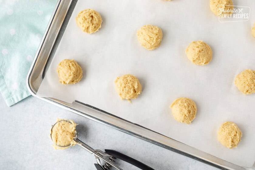 Baking sheet with parchment paper and scoops of Italian Easter cookie dough.