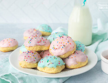 Plate of Italian Easter cookies frosted with pink, purple and blue icing and sprinkles.