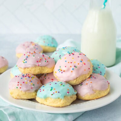 Plate of Italian Easter cookies frosted with pink, purple and blue icing and sprinkles.