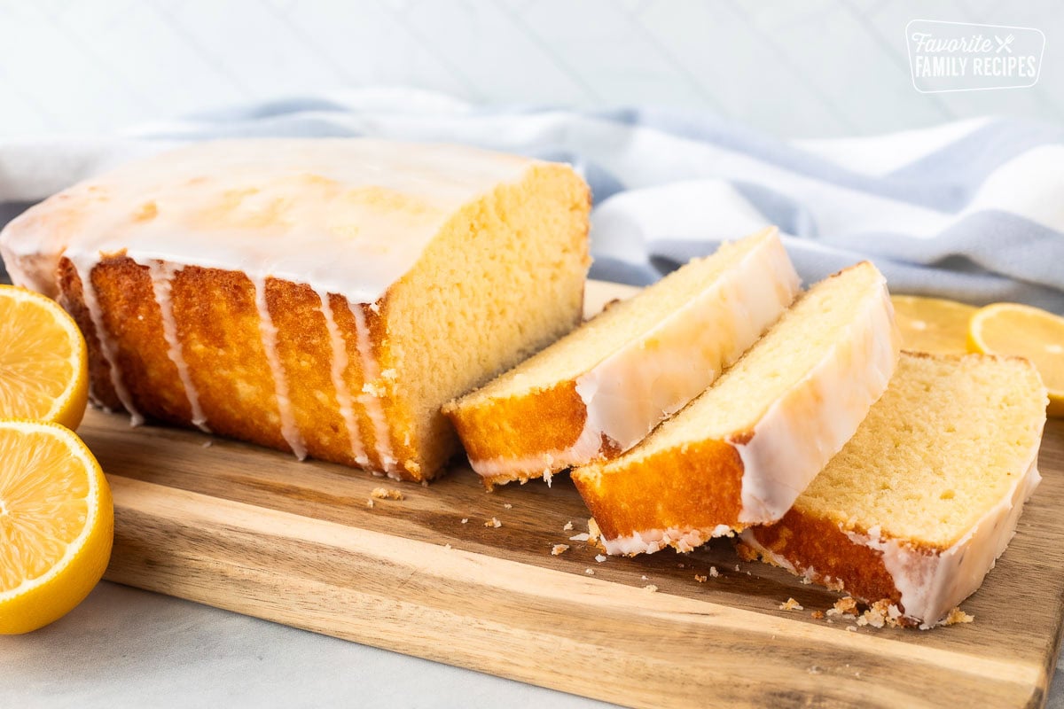 Three slices of lemon pound cake on a wooden cutting board.