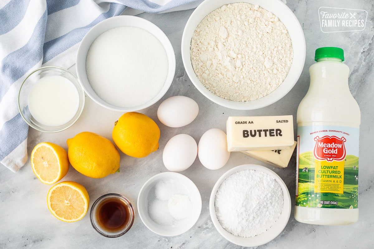 Ingredients to make lemon pound cake including buttermilk, butter, powdered sugar, eggs, flour, sugar, milk, lemons, vanilla, baking soda, baking powder and salt.