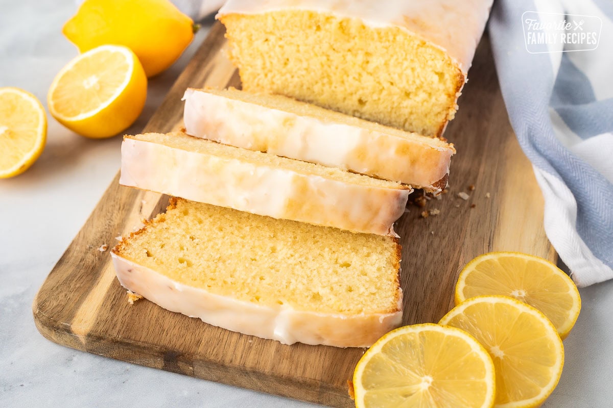 Sliced glazed lemon pound cake on a wooden cutting board.