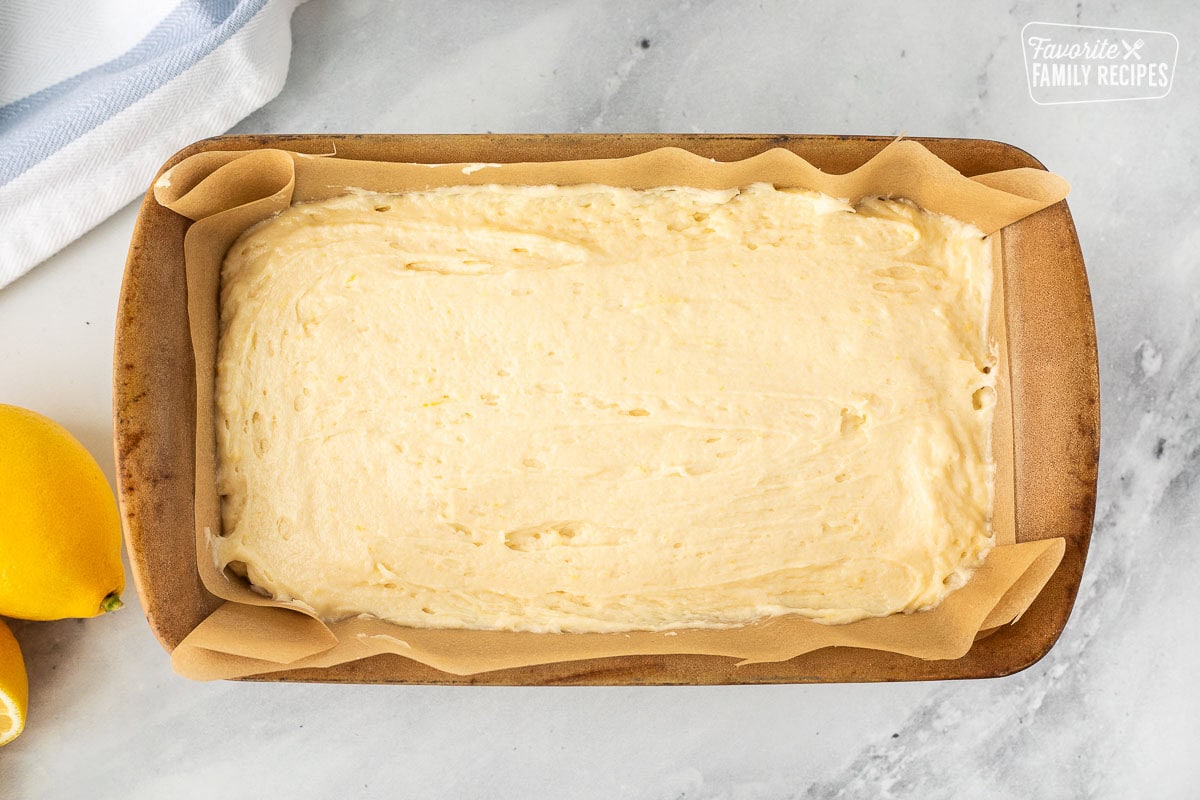 Loaf pan lined with parchment paper and lemon poundcake batter.