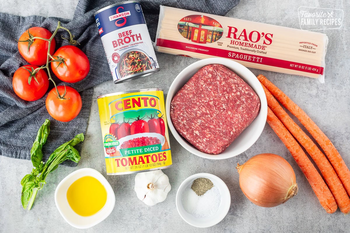 Ingredients to make Nick's Authentic Italian Spaghetti including pasta, carrots, onions, ground beef, salt, pepper, sugar, garlic, olive oil, canned tomatoes, beef broth and fresh basil.