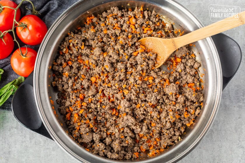 Cooked ground beef and vegetables in a skillet for Italian spaghetti sauce