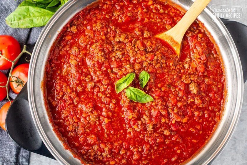 Rich and meaty pasta sauce for Italian spaghetti in a skillet garnished with fresh basil.