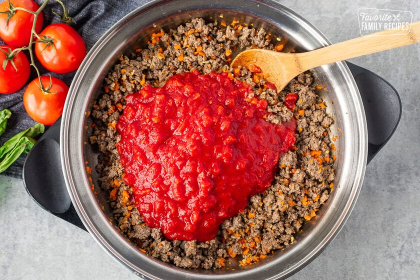 Canned San Marzano tomatoes added to meat mixture to make spaghetti sauce.