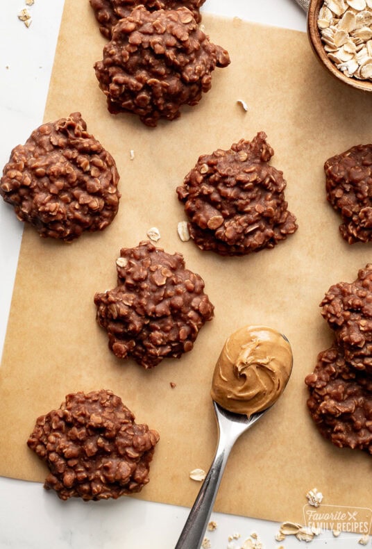 No bake cookies on brown parchment paper with a spoon of peanut butter next to them