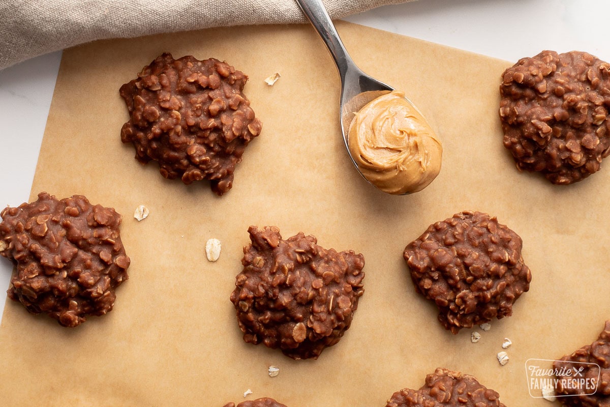 Classic No bake cookies on parchment paper with a spoon of creamy peanut butter