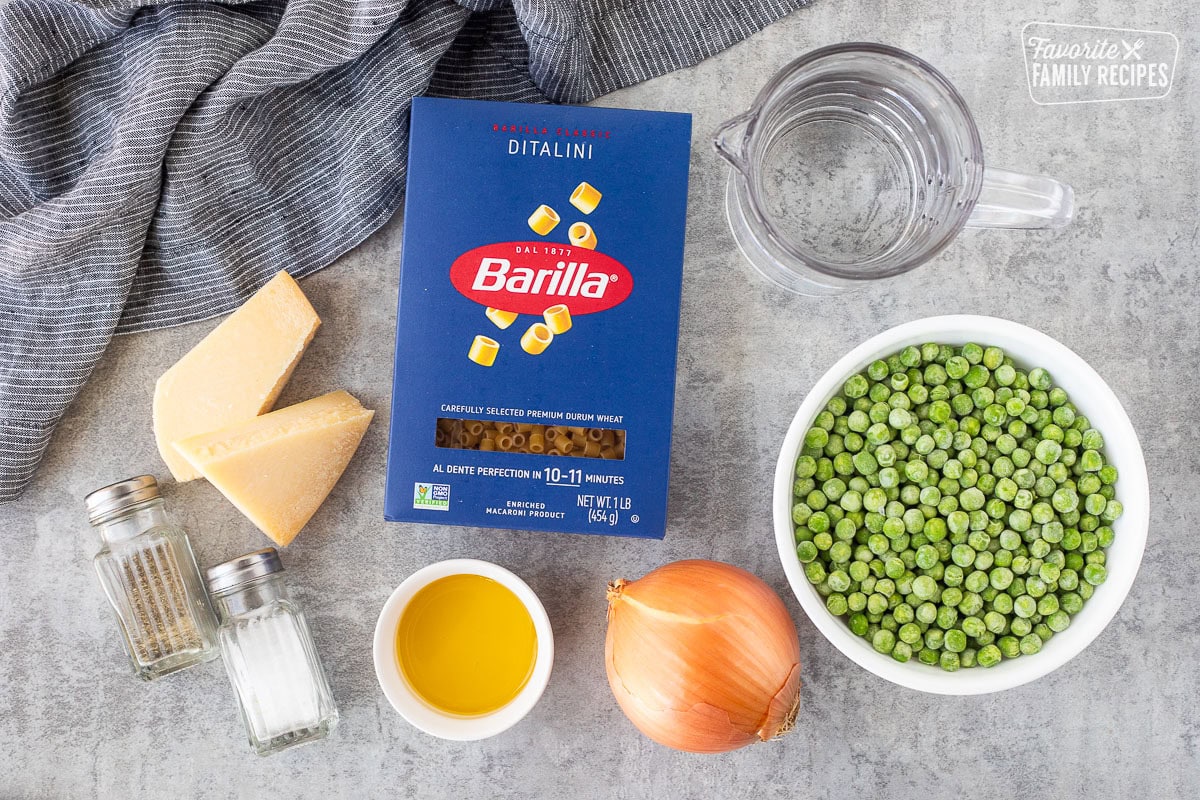 Ingredients to make pasta with peas including frozen peas, the ditalini pasta, olive oil, onion, water, salt, pepper and cheese.