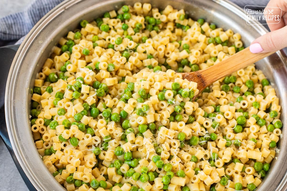 Skillet of Pasta with peas and a wooden spoon