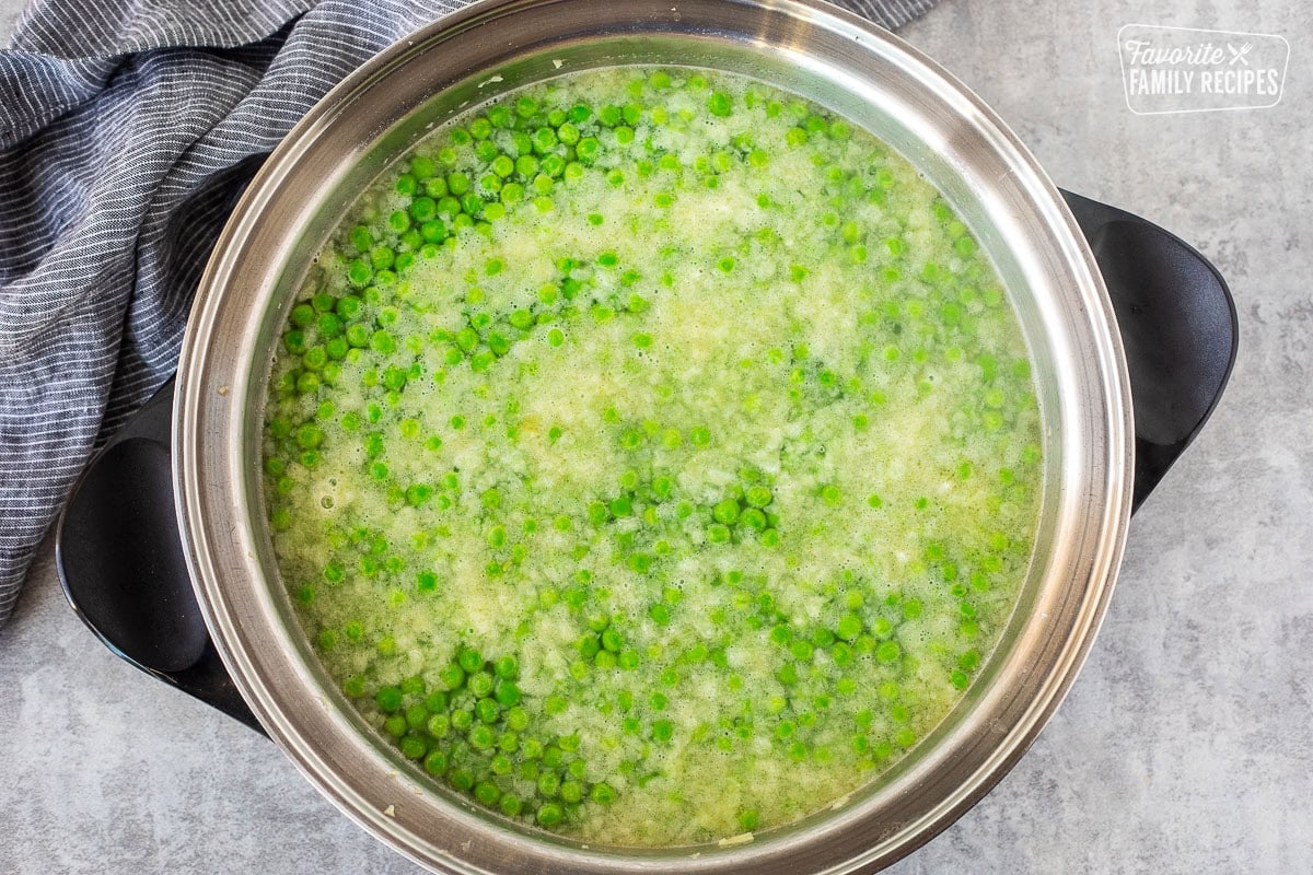 Skillet with water added to peas mixture.