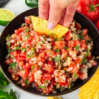 Dipping a chip into a bowl of Pico de Gallo with fresh cut tomatoes, onion, cilantro and jalapeño.