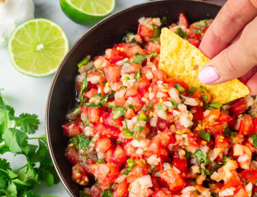 Dipping a chip into a bowl of pico de gallo.