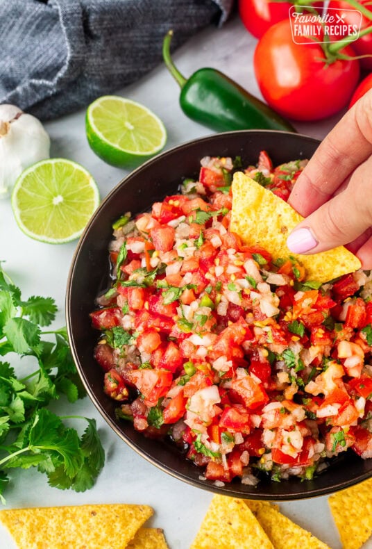 Dipping a chip into a bowl of pico de gallo.