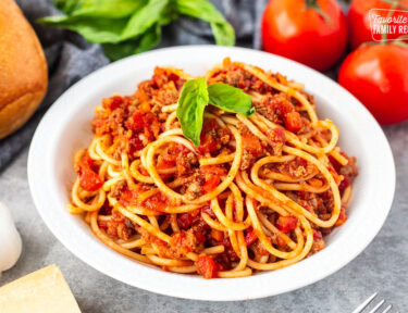 Nick's Authentic Italian Spaghetti on a plate with fresh basil leaves.