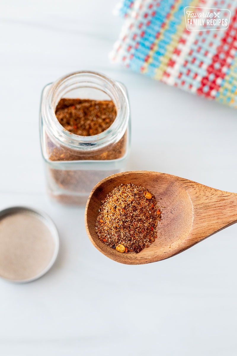 Spoon with Carne Asada seasoning. small glass, spice jar of savory Carne Asada seasoning on the side.