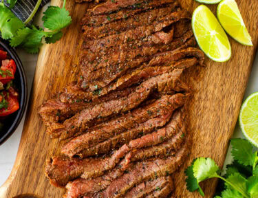 Grilled Carne Asada meat marinated, grilled, and sliced on a cutting board for serving.