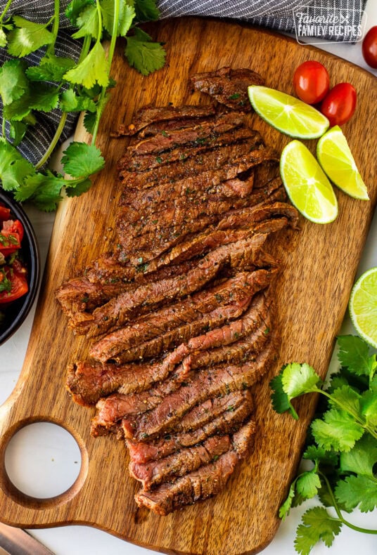 Grilled Carne Asada meat marinated, grilled, and sliced on a cutting board for serving.