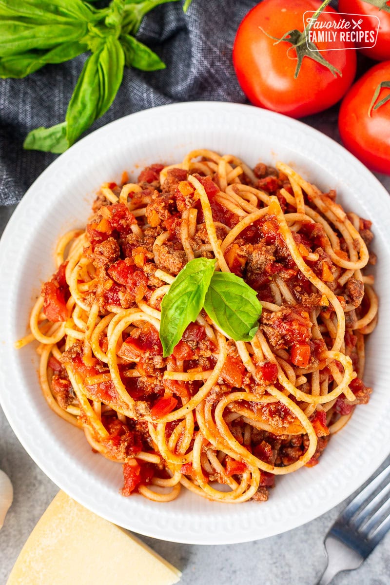 Classic spaghetti with rich Italian meat sauce garnished with fresh basil.