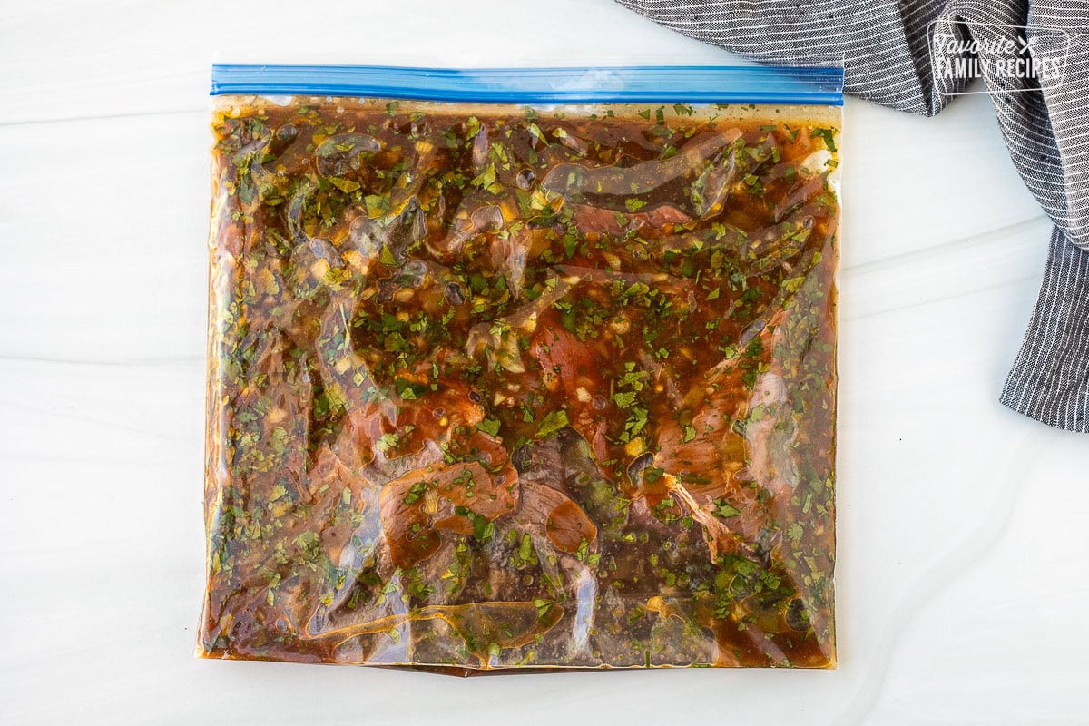 Ziplock bag with carne asada marinating with carne asada seasoning and fresh chopped cilantro.