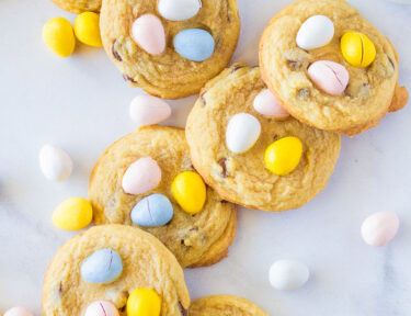 An overhead look at 7 Cadbury Egg Cookies for Easter with Cadbury Mini Eggs scattered in the background.