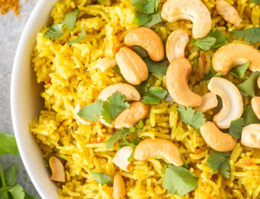 Bowl of coconut rice with cashews and cilantro.