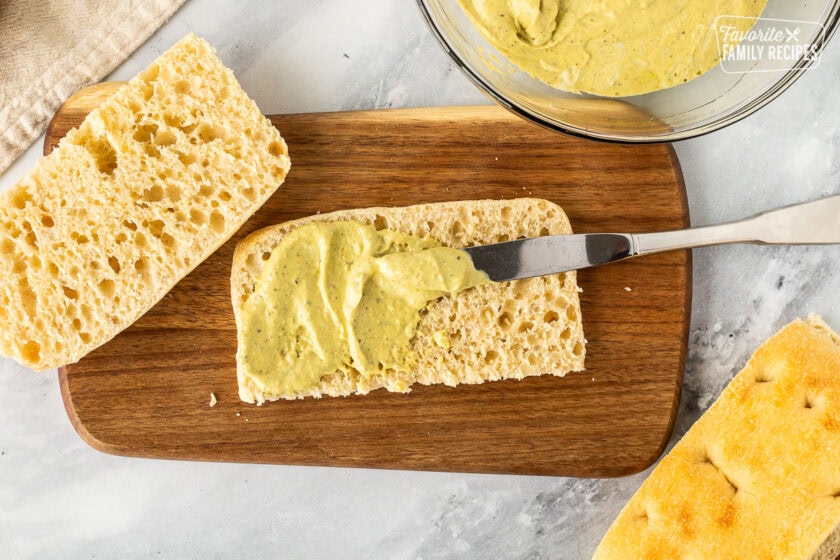 Spreading pesto mayo on bread.