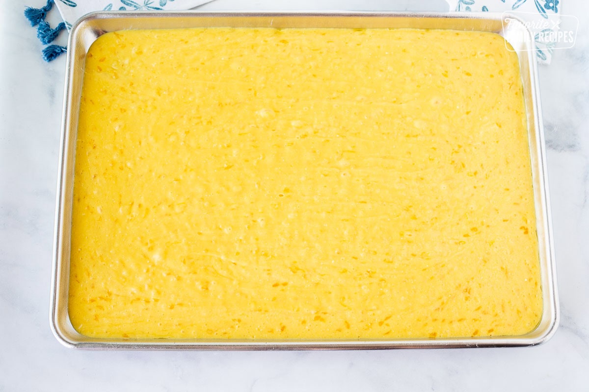 Orange pineapple cake batter in a baking sheet.