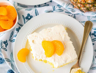 Orange pineapple cake slice on a plate with a fork.