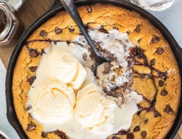 Pizookie with melted ice cream in a skillet with a spoon.