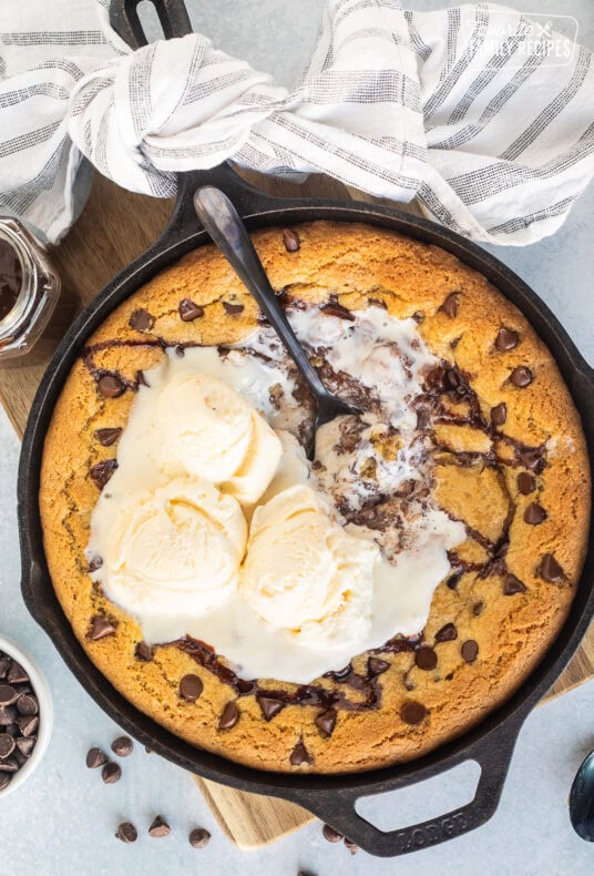 Pizookie with melted ice cream in a skillet with a spoon.