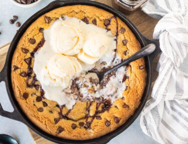 Pizookie with melty ice cream in a skillet with a spoon.