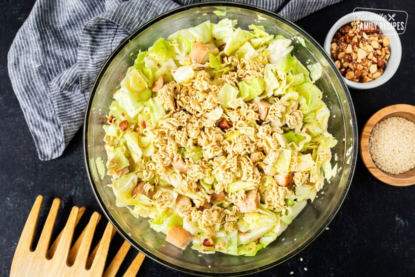 Glass mixing bowl with Bowl of Ramen Noodle Salad (Pai Mai topped with almonds, sesame seeds and season toasted ramen noodles.