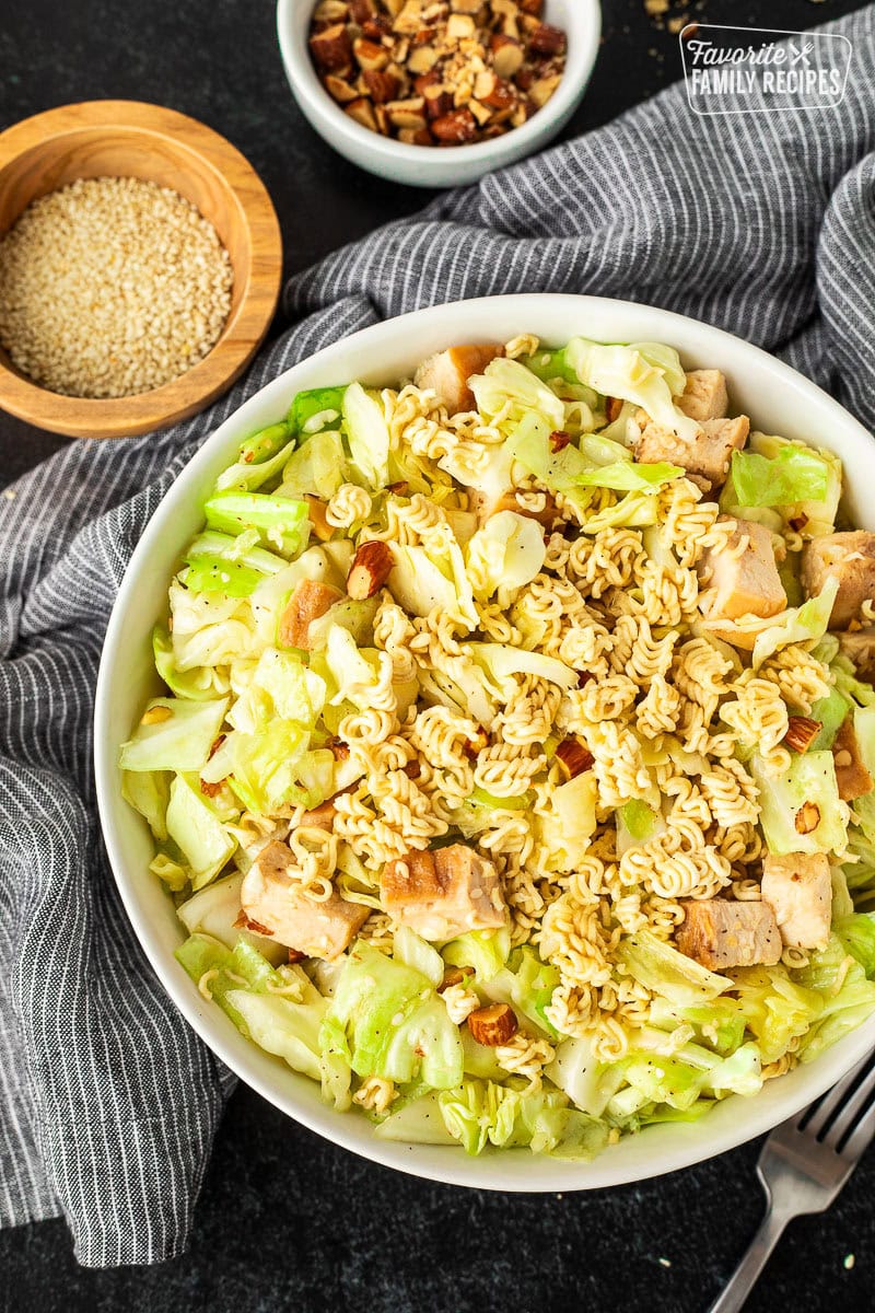 Mixing bowl of Ramen Noodle Salad (Pai Mai) with salad tongs.