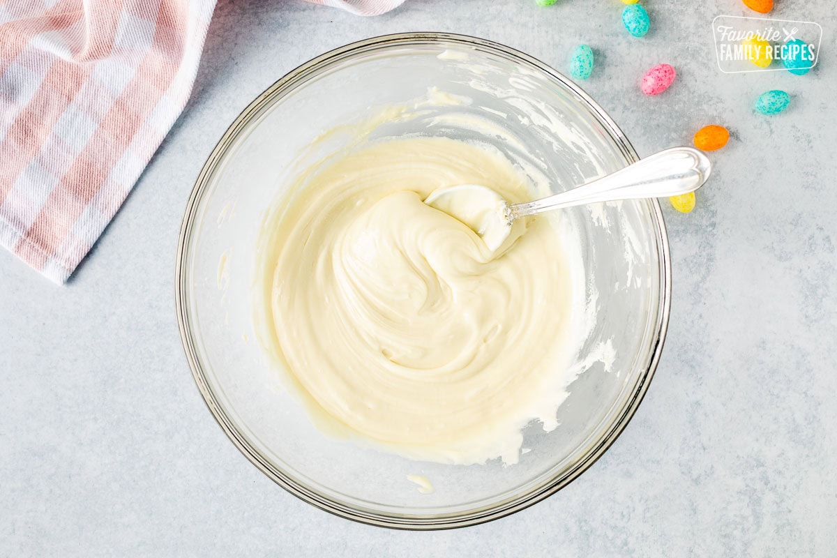 Mixing bowl of melted white chocolate chips with a spoon.