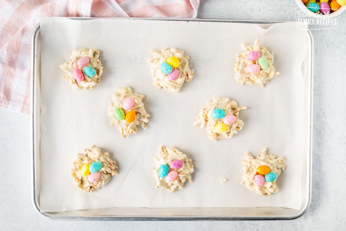 White chocolate bird nests with jelly beans on a baking sheet.